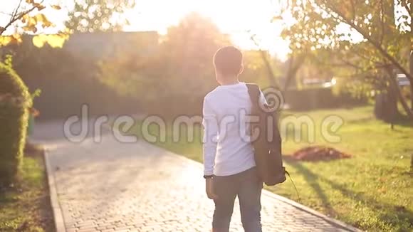 回到男生的视野放学回家穿着白衬衫牛仔裤和背包的青少年视频的预览图