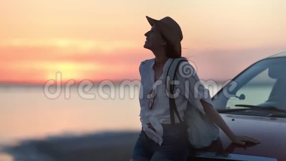 放松的背包客微笑的女人在日落时享受自然海景在汽车旅行中中镜头视频的预览图