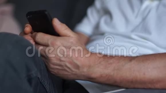 一位微笑的灰胡子老人的肖像他手里拿着智能手机他打字扫描视频的预览图