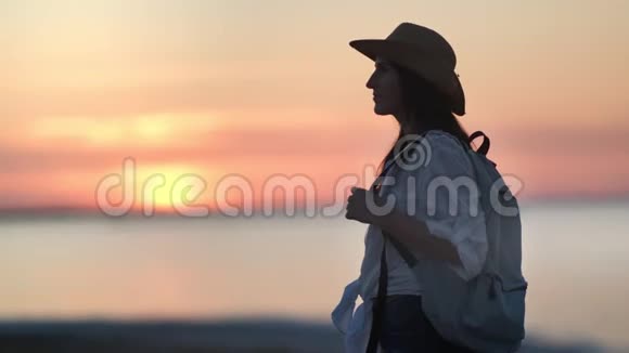 疲惫的旅行背包客女性在日落时放松享受傍晚美丽的海景中景视频的预览图