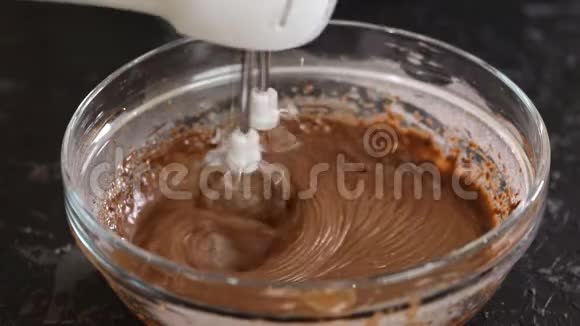 用可可搅拌巧克力面团巧克力面团在玻璃碗中与搅拌机混合视频的预览图