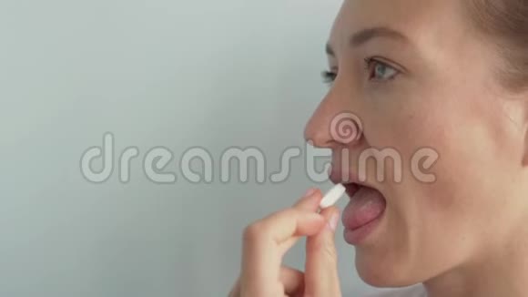 一个女人吞下一个白色的大药丸用杯子里的水喝它视频的预览图
