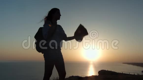 成功的背包客女性在日落时分把帽子戴在山顶视频的预览图