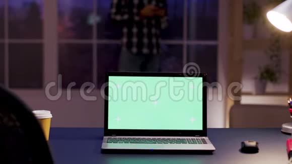 把绿色屏幕笔记本电脑装在家庭办公室的桌子上视频的预览图