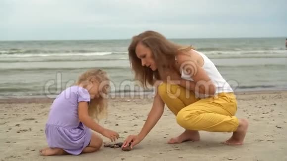妈妈和小女儿在海滩上玩石子视频的预览图