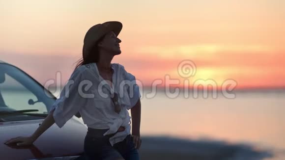 时尚微笑旅游女性放松坐在车帽欣赏夕阳中射视频的预览图