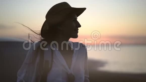 性感的旅行女人戴着帽子挥舞着头发微笑着欣赏着美丽的日落在汽车旅行中视频的预览图