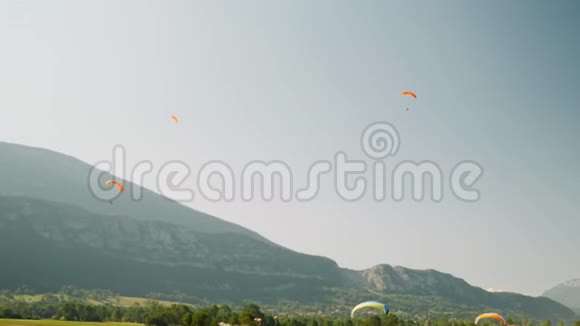 一群活跃的人在滑翔伞上飞行背景是蓝天和山脉Paraplane跑道在A中飞行滑翔伞视频的预览图