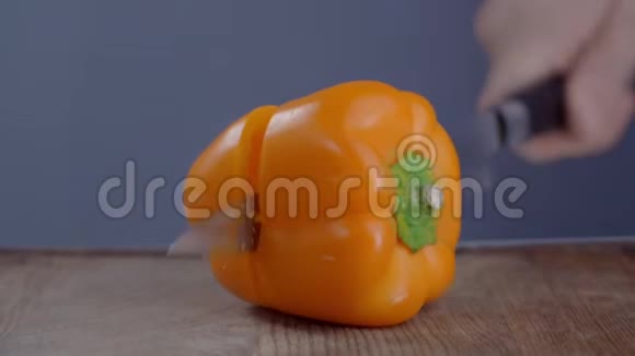 厨师慢慢地在木板上把橙铃椒切成两半切蔬菜做新鲜沙拉视频的预览图