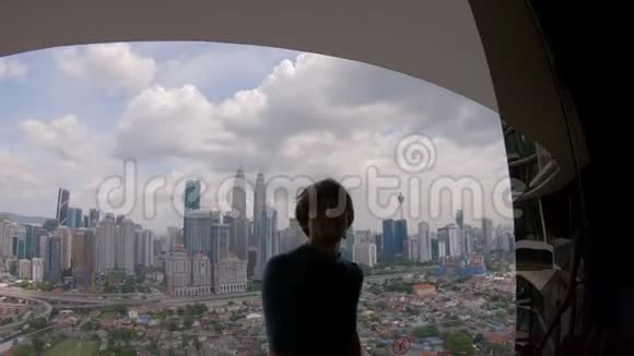 慢镜头年轻人正在自拍坐在视点上在吉隆坡市中心欣赏风景旅费视频的预览图