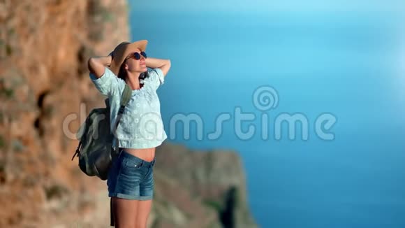 微笑的旅行晒黑的女人放松的上升的手站在山上的海面上感受积极的情绪视频的预览图