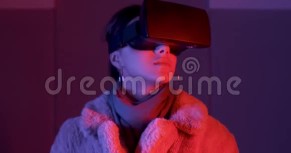 美丽的年轻女子使用虚拟现实眼镜霓虹灯照明背景喜欢触摸虚拟的女孩视频的预览图