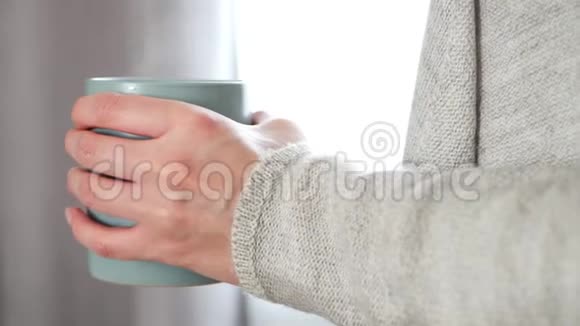 女性手拿着一杯热饮特写蒸汽来自杯子女孩喝茶或咖啡站在视频的预览图