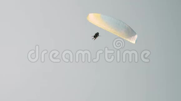 五颜六色的孤立滑翔伞正降落在阿尔卑斯山山脉上方灰色多云的天空上坐滑翔伞的男人视频的预览图