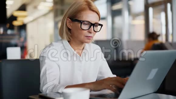 公司经理成熟女士在咖啡厅使用笔记本电脑打字商务电子邮件视频的预览图