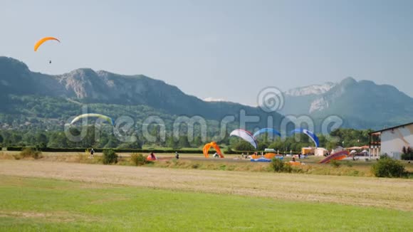 在阿尔卑斯山滑翔伞站的副车道课程运动员在蓝天和高山上滑翔伞起飞视频的预览图
