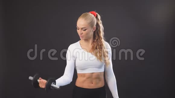 强壮肌肉的女人拿着哑铃对着镜头摆姿势视频的预览图