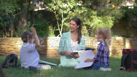 现代教育方法学生男女同校女教师在草坪上看书和聊天视频的预览图
