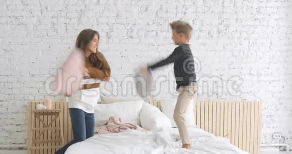 幸福的家庭母子在家里的托儿所的床上打着滑稽的枕头视频的预览图