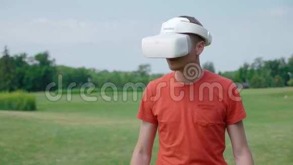 一名男子在公园里使用VR耳机躲避障碍物环顾四周视频的预览图