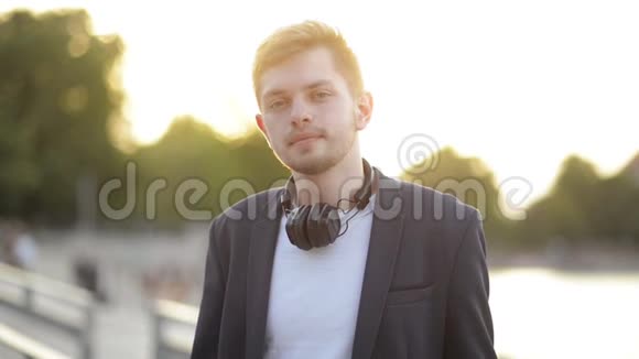 白人学生男孩听音乐的肖像戴着耳机的快乐笑男看镜头视频的预览图