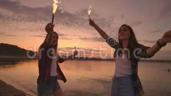 美丽的女人在夏天与火花在海滩上缓慢的动作在晚上跳舞视频的预览图