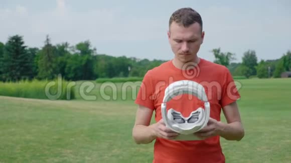 一个男人把VR耳机放在头上在公园里玩虚拟游戏视频的预览图
