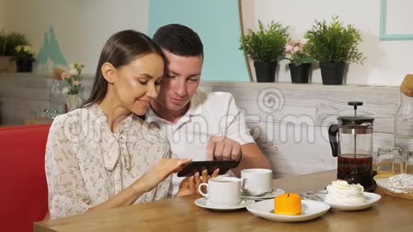 女孩和男孩在糖果店的餐桌上看手机视频的预览图