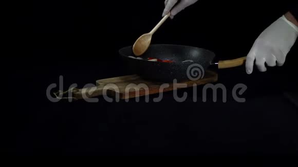 厨师用黑色背景的木勺在锅里搅拌蔬菜视频的预览图