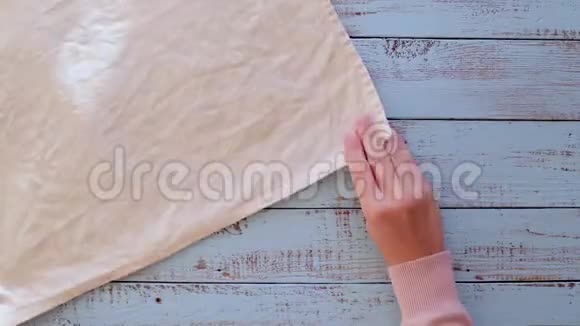 女性手把不同颜色的亚麻餐巾纸叠在一张木制的旧桌子上视频的预览图