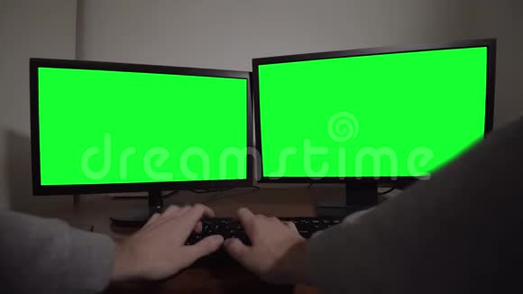 双手在带有绿色屏幕的两个显示器上键入键盘视频的预览图