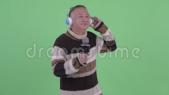 快乐成熟的日本男人听音乐用麦克风唱歌视频的预览图