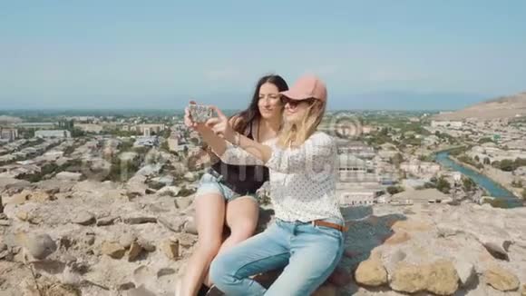 两个最好的朋友去国外旅行了很长一段时间女士们坐在第比利斯的石栅栏上自拍视频的预览图
