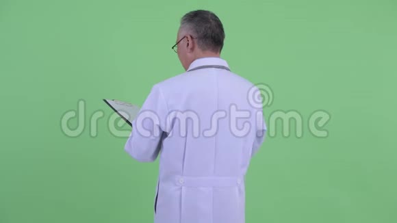 快乐成熟的日本男子医生用剪贴板检查后景视频的预览图