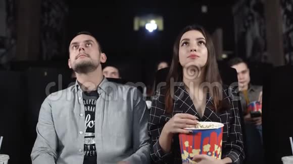 快乐的一对夫妇在电影院看电影享受他们的约会视频的预览图