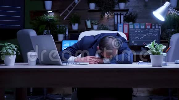 工作过度的商人晚上在办公室睡着了视频的预览图