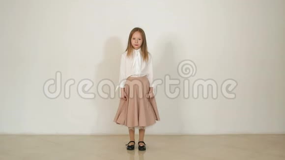一个可爱的小女孩穿着长裙跳跃在白色的背景上玩得很开心视频的预览图