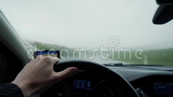 男子握着方向盘在雨中驾驶汽车在雨天小心驾驶左手驾驶关门视频的预览图