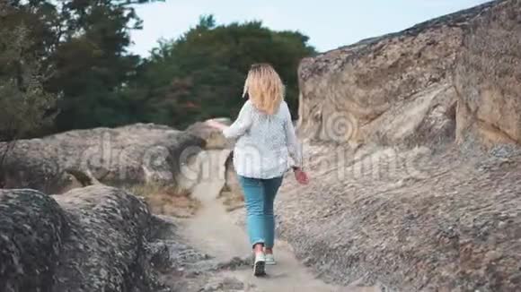 快乐的女孩在度假在岩石的背景下在山上散步他带着灿烂的笑容环顾四周视频的预览图