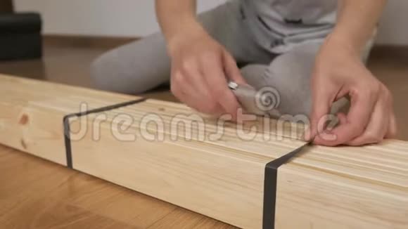一个女人拆了一个木架在商店里买了用刀切包装胶带手拿刀特写视频的预览图