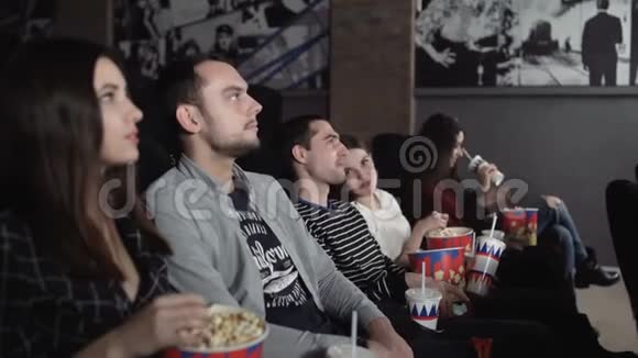 快乐的朋友在剧院看电影情侣和其他人一边看电影一边吃爆米花一边喝汽水视频的预览图