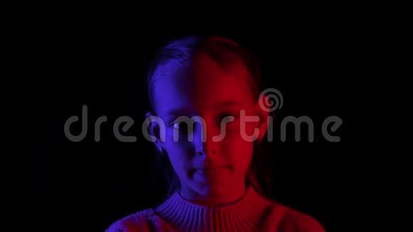 可爱的严肃少女在黑暗中看镜头的肖像视频的预览图