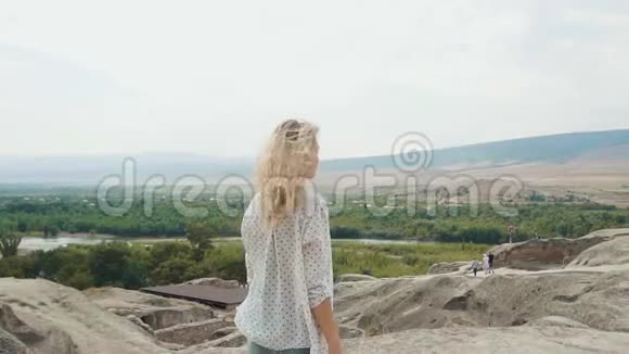漂亮漂亮的金发美女从高高的悬崖上俯瞰美丽的乔治亚州景色视频的预览图