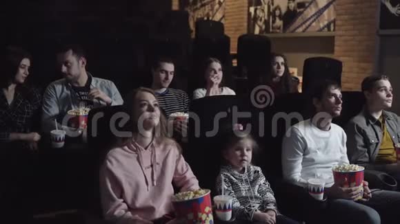 年轻人坐在电影院看电影吃爆米花友谊和娱乐的概念视频的预览图