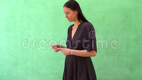 绿色背景下戴着智能手机的年轻美女画像视频的预览图