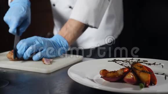 厨师在餐厅厨房做饭快关门手在手套切片烤肉的背景慢镜头视频的预览图