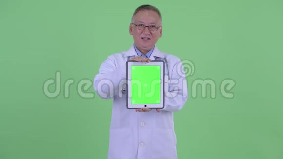 快乐成熟的日本男医生一边展示数码平板一边聊天视频的预览图