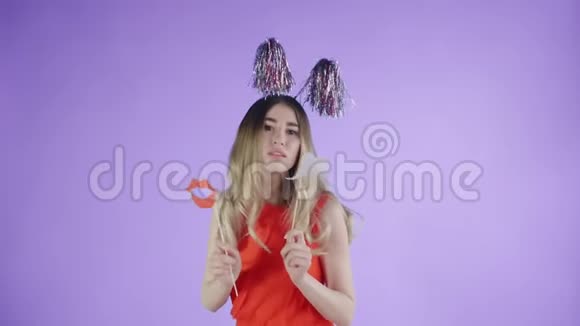 戴着派对帽和纸板胡子的漂亮女孩正在紫色背景上跳舞视频的预览图