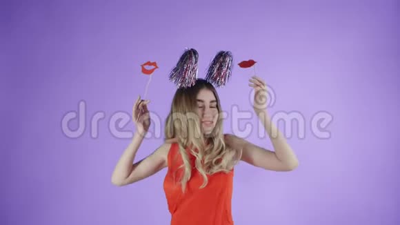 戴着派对帽的漂亮女孩在紫色背景下的肥皂泡下跳舞视频的预览图