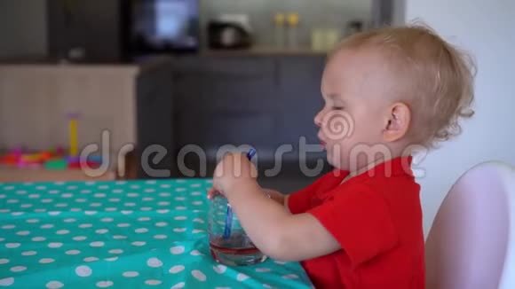 快乐的小男孩坐在桌子旁喝果汁的肖像万向节运动视频的预览图